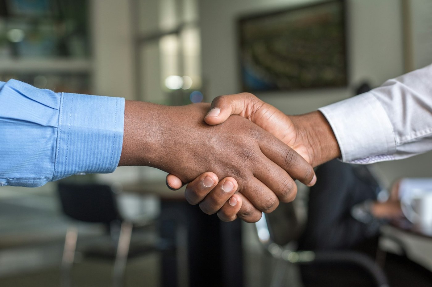 Two people agreeing a deal with a handshake in an office